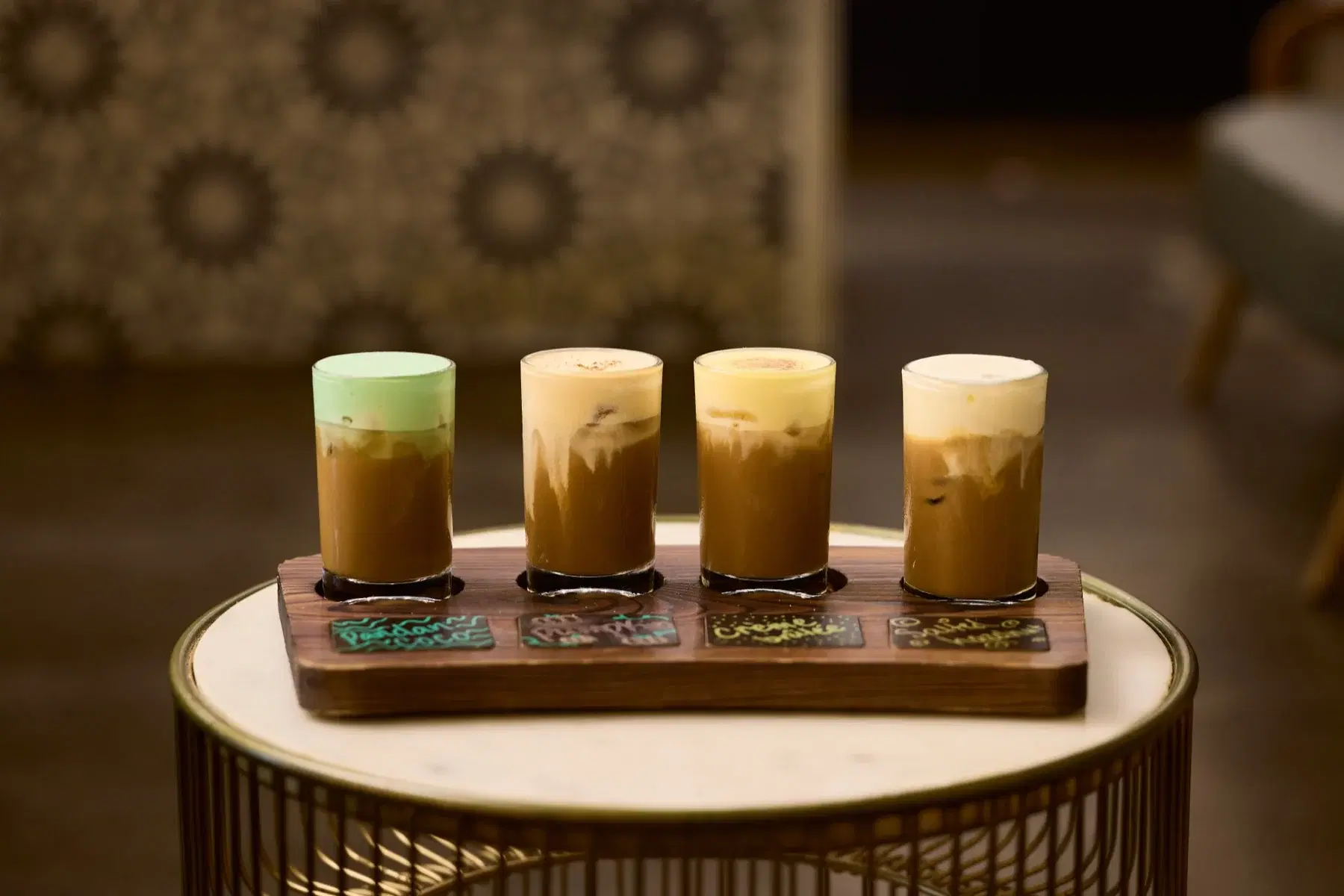 A flight of four iced drinks on a wooden serving tray