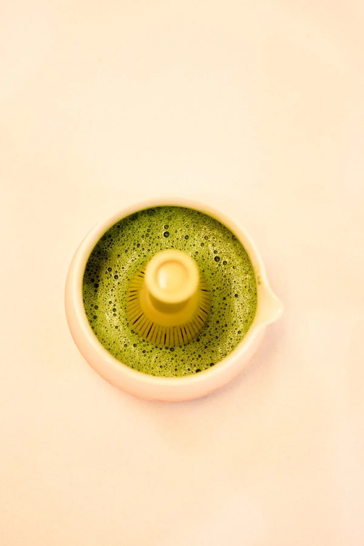 Top-down view of ceremonial matcha in a small white bowl with whisk imprint